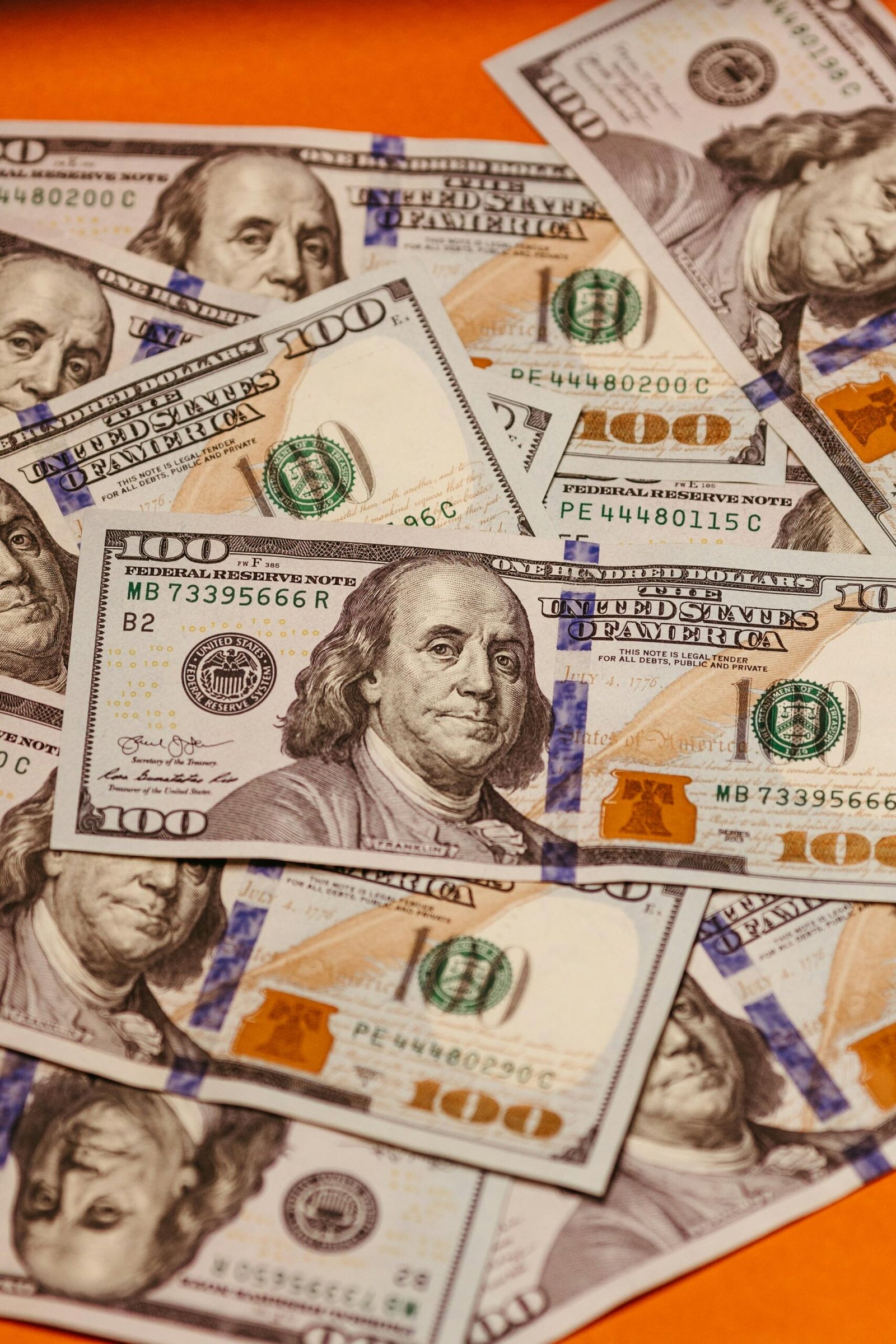 Stack of crisp one hundred dollar bills with visible details and security features.